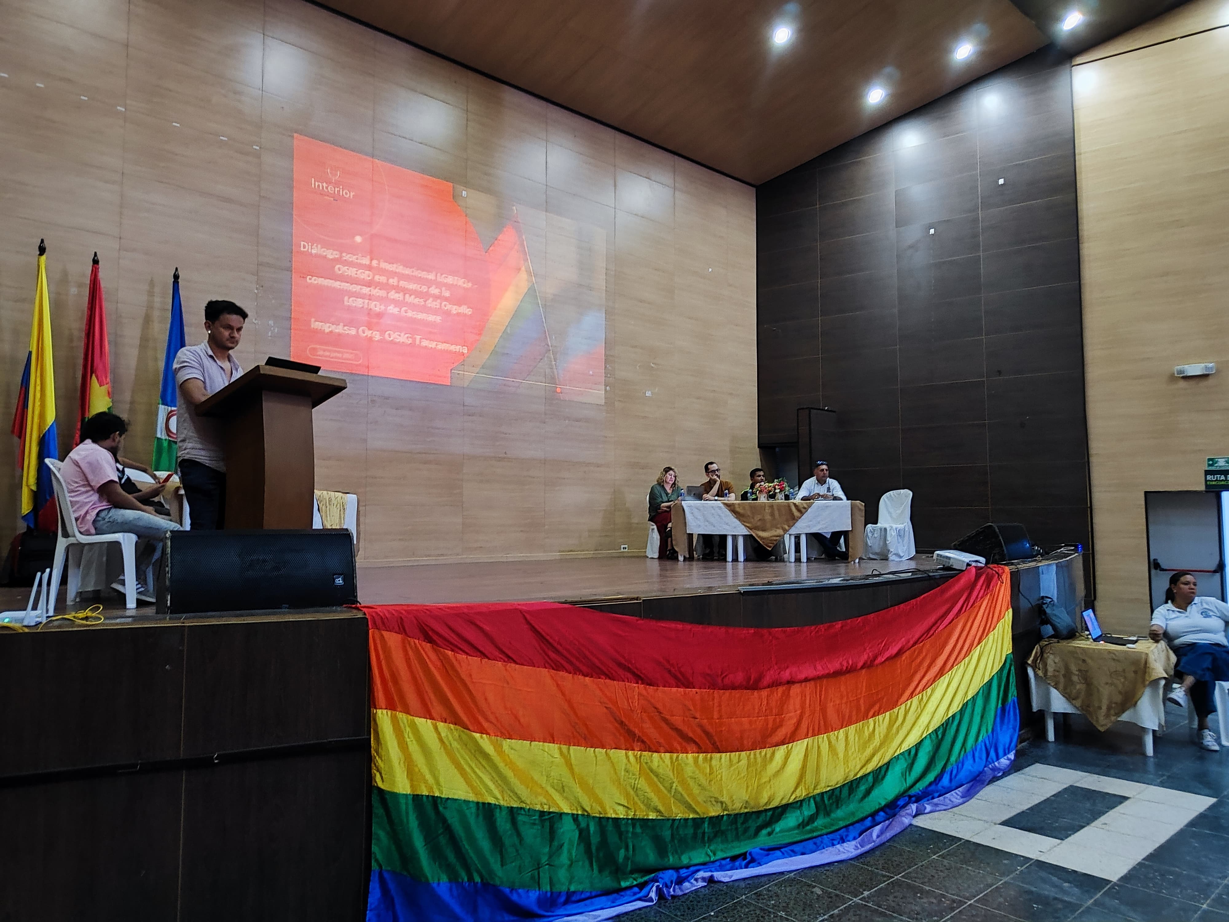 Tarima de la jornada de socialización del CONPES 4147 con la bandera LGBTIQ+.