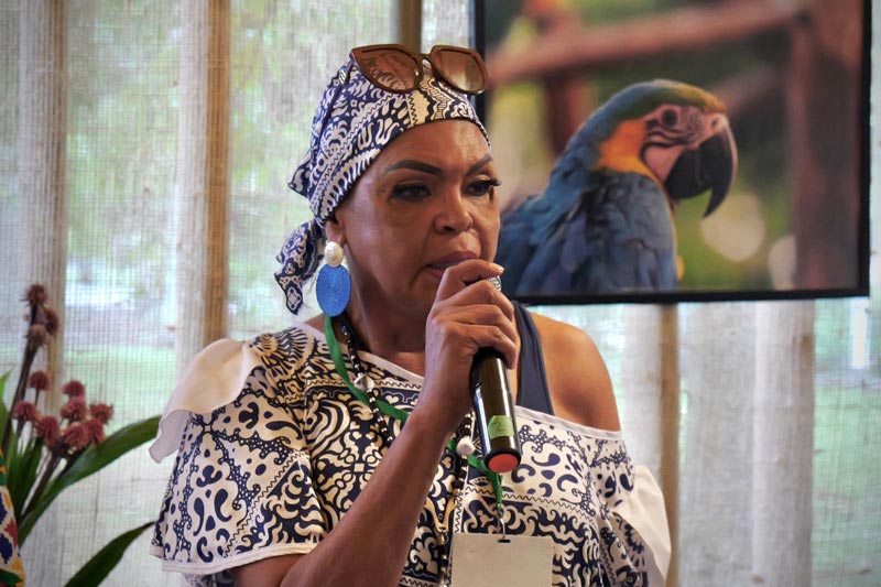 Mujer afro, interviene en la charla. El micrófono lo sostiene en la mano derecha 