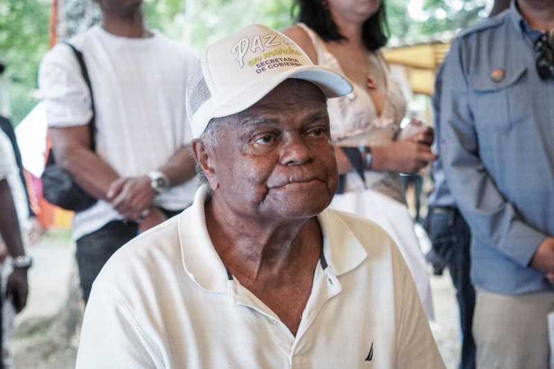 Adulto mayor raizal, lleva gorra y camiseta blanca. Está atento en la charla 