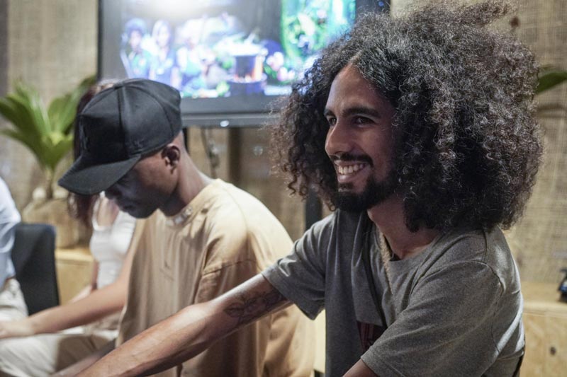 Hombre joven con cabello rizado, barba cerrada y sonrisa expresiva 