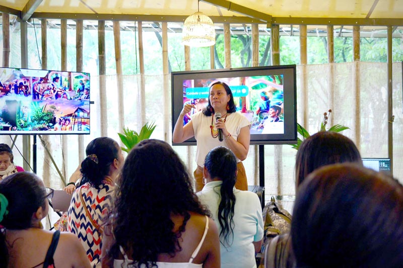 Mujer de edad media, dicta charla a grupo de personas sobre temas de sostenibilidad