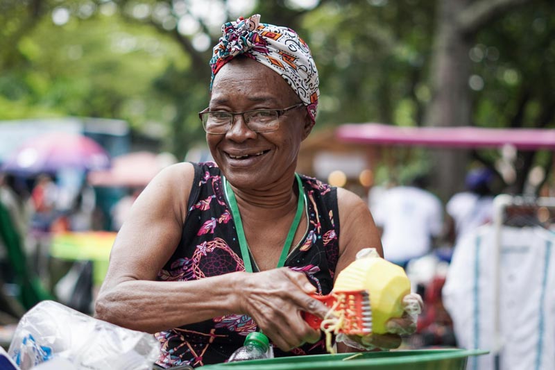  Vendedora ambulante de fruta, sonríe mientras pela un mango biche.