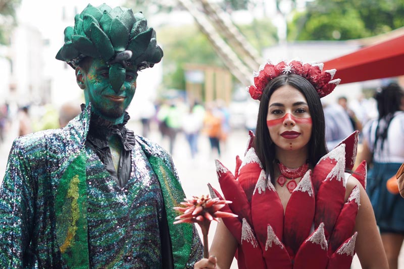 Hombre con traje verde representando la naturaleza y la mujer esta vestida con un traje rojo emulando las flores.  