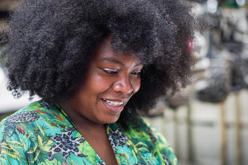 Mujer Afro sonriente, observando un producto que le llama la atención.