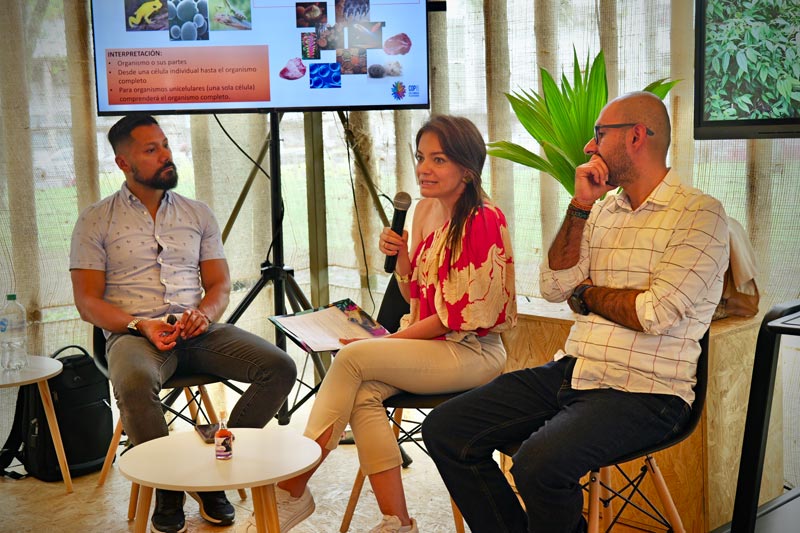 Mujer sentada en medio de dos hombres, que son conferencistas del panel ambiental DNP en la COP16.