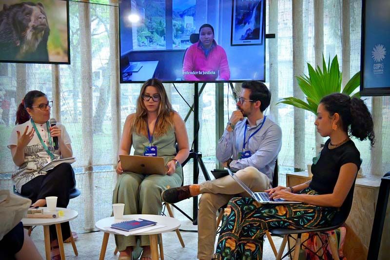 Grupo de conferencistas, tres mujeres y un hombre, socializando con la comunidad. 