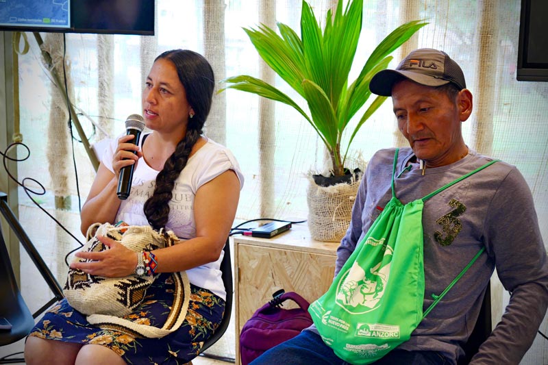 Mujer rural, guardiana del ambiente aportando sus conocimientos en la conferencia, sentada junto a un hombre del campo.