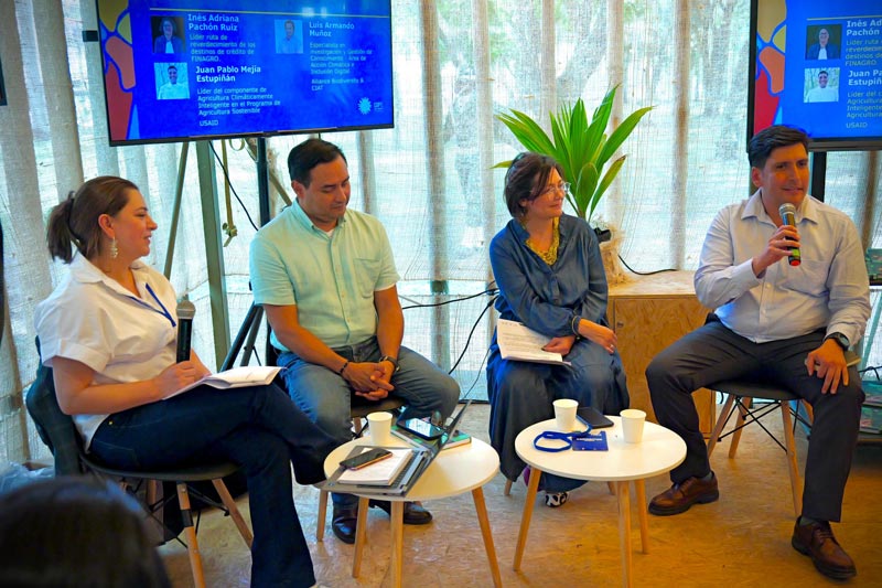 Sentados en el panel principal, dos hombres y dos mujeres, frente a ellos un grupo de personas que los escuchan atentamente.