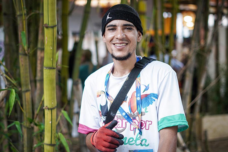 Joven sonriendo, lleva puesta una camiseta colorida y guantes rojos. 