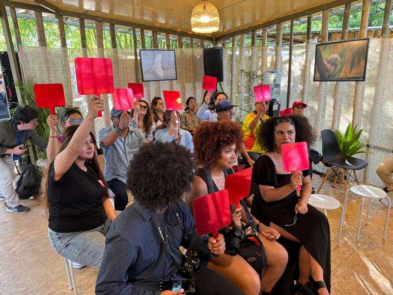 Grupo de personas, participan  en la actividad +Clima, levantando paletas rojas.