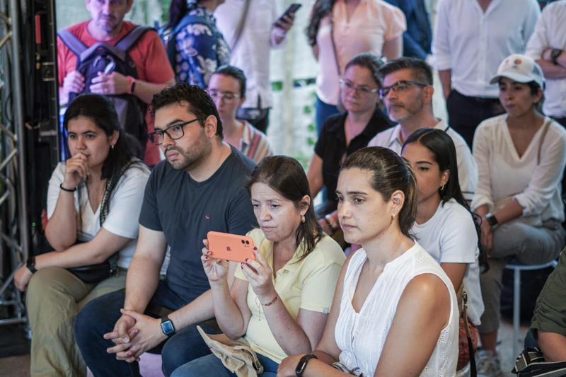 Auditorio lleno, en primera línea cuatro personas. Una de ellas graba las intervenciones de los panelistas.    