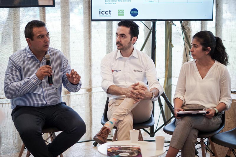 Tres panelistas. Uno de ellos  tiene el micrófono y está dando una explicación sobre transporte.  