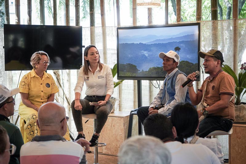 Grupo de personas, rodean a los panelistas interactuando entre ellos.  