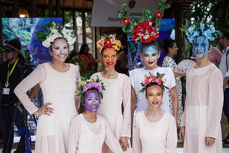 Seis mujeres, visten túnicas blancas, todas llevan maquillaje artístico de animales y plantas 