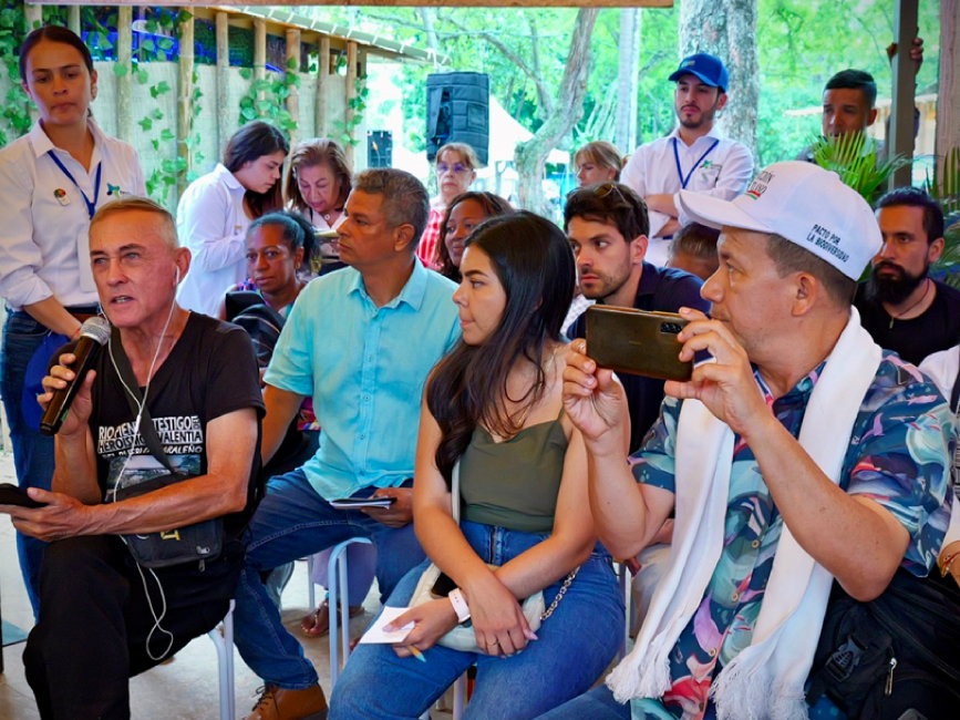 Estand lleno, todos los asistentes prestan atención al hombre extranjero que interviene.