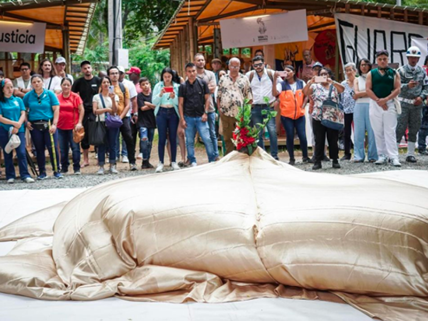 Grupo de personas se reúnen frente a los estand del DNP y Justicia  para ver una muestra de arte.